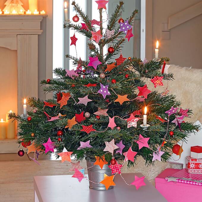 Kleiner Tannenbaum mit Sternenkette aus unterschiedlichen Geschenkpapieren und glitzernden Minikugeln.